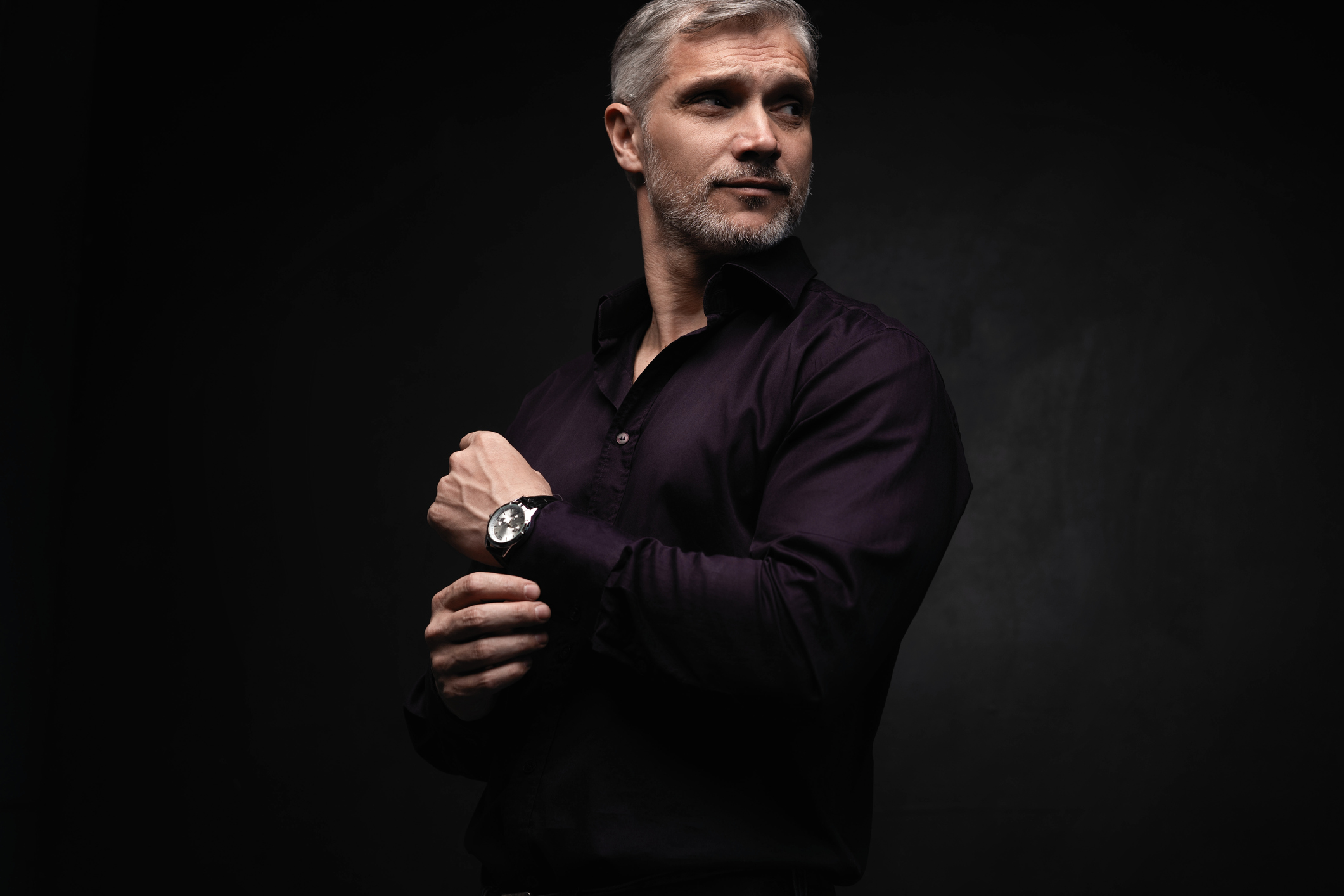 Handsome man posing in black shirt on dark background in studio